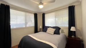a bedroom with a bed and two windows at Drakes Hideaway in Golden Beach