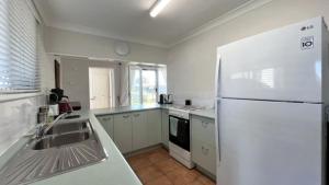 a kitchen with a white refrigerator and a sink at Drakes Hideaway in Golden Beach