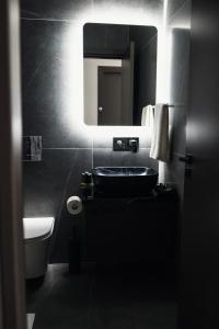 ein schwarzes Badezimmer mit Waschbecken und Spiegel in der Unterkunft Rois Constructions in Nikosia + 5 Fotos