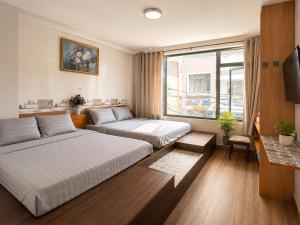 a hotel room with two beds and a television at Thiên Ngân Hostel in Da Lat