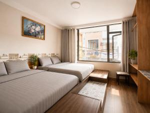 a hotel room with two beds and a window at Thiên Ngân Hostel in Da Lat