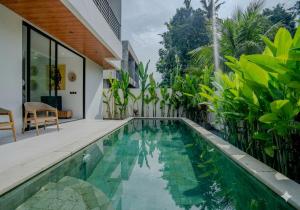 an infinity pool in the backyard of a house with green plants at Santara Villa Ubud in Ubud