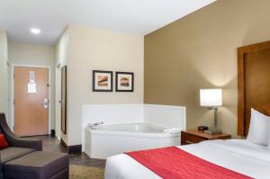 a hotel room with a bed and a bath tub at Comfort Inn & Suites Covington - Mandeville in Covington