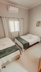 two beds in a room with a window at Aconchego do Peruaçu in Itacarambi