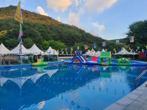a pool of water with tents and a mountain at Goesan Joryeong Pension in Koesan