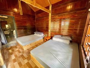a room with two beds in a wooden cabin at Red Dao Homestay and Entire bungalow in Tả Van