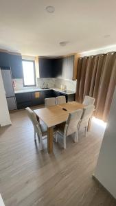 a kitchen with a wooden table and white chairs at SunVillaTuzi in Tuzi