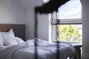a bed with white sheets and a window at Solo Society Hybrid Hotel Vilnius in Vilnius