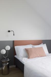 a white bed with a red pillow and a lamp at Solo Society Hybrid Hotel Vilnius in Vilnius