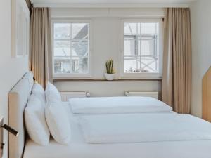 two beds in a bedroom with two windows at MYA Weinland Hotel Kobern-Gondorf in Kobern-Gondorf