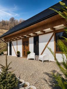 a house with two white chairs and a building at The White House Tripsylvania in Şirnea