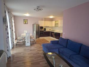 a living room with a blue couch and a kitchen at Hotel Seasons 3 in Sunny Beach