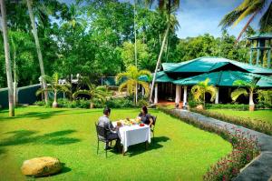 a man and woman sitting at a table in the grass at The Kings Villa in Kandy