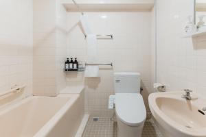 a white bathroom with a tub and a toilet and a sink at Portside Stay 石垣島 離島ターミナル徒歩3分 バスターミナル前 室内リニューアル in Ishigaki Island +43 photos
