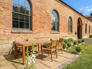 a wooden table and chairs in front of a brick building at West Stable in Retford