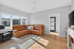 a living room with a brown couch and a television at Hutchinson House in Goolwa