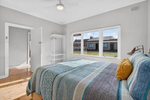 a white bedroom with a bed and a window at Hutchinson House in Goolwa