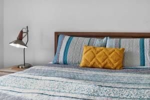 a bed with a blue comforter and a yellow pillow at Hutchinson House in Goolwa +25 photos