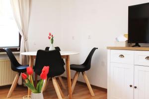 a dining room table with black chairs and a vase of flowers at Ferienwohnung im Rauchwinkel in Hösseringen