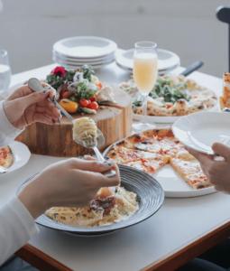 a group of people sitting at a table eating pizza at 森の宿 l ACAO FOREST 01 in Atami