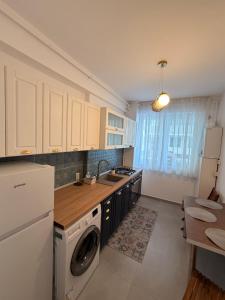 a kitchen with white cabinets and a washer and dryer at Happy Studio 1 in Craiova
