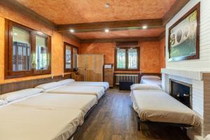 a row of beds in a room with a fireplace at Casa Viria in Navaluenga