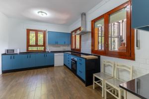 a kitchen with blue cabinets and wooden floors and windows at Casa Viria in Navaluenga