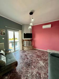 a living room with a red wall and a couch at Errant Blue House Kyllini in Kyllini