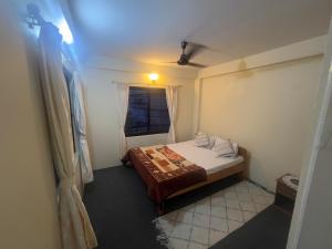 a small bedroom with a bed and a window at Namaste Apartment in Pokhara