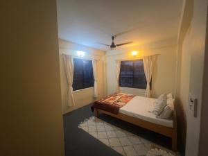a bedroom with a bed and two windows at Namaste Apartment in Pokhara