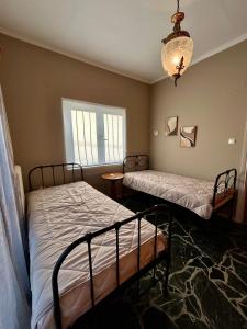 a bedroom with two beds and a chandelier at Errant Blue House Kyllini in Kyllini