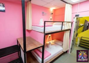 a room with three bunk beds in a pink room at DISCO ZOO Bar & Hostel in Haad Rin