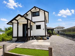 a small white house with a black roof at Hamabun テラスでBBQ 湖まで徒歩5分 無料駐車場3台 in Takashima
