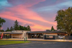 a building in a parking lot with a sunset at Fairway Inn and Suites, an Ascend Collection Hotel in Mishicot