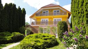 a yellow house surrounded by trees and bushes at Magyar Apartmanház IV. in Zalakaros