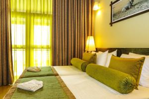a hotel room with a large bed with green pillows at Oak Ray Wild Yala in Tissamaharama +27 photos