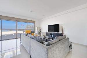 a living room with a couch and a television at Spacious Sea-View Penthouse + Big Balconies in Ashdod