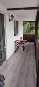 a porch with a bench and a table and a window at Casa ALBERT in Brezoi