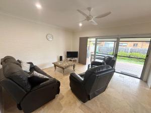 a living room with two leather chairs and a table at Three Fifty Four Straight St Hat Head - Bring your own linen. in Hat Head