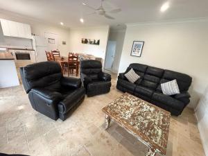 a living room with black leather furniture and a table at Three Fifty Four Straight St Hat Head - Bring your own linen. in Hat Head