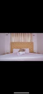 a bed with a wooden headboard with a towel on it at ShanazNest in Bulawayo +2 photos