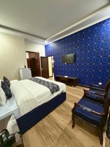 a bedroom with a bed and a blue wall at Hotel de Raj Sialkot in Sialkot