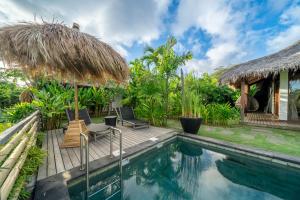 a villa with a swimming pool and a hut at La Reserva Villas Bali in Jimbaran