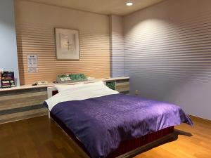 a bedroom with a bed with a purple blanket at adult only ホテルシャルム in Itoigawa
