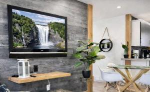 a living room with a tv hanging on a wall at Le Wolfe - 2 Bedrooms - 2 min Falls - Free Parking in Boischâtel