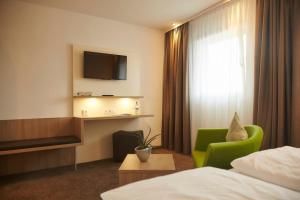 a hotel room with a bed and a green chair at Flair Hotel Grüner Baum in Donaueschingen