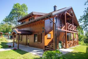 a log cabin with a porch and stairs to the front at Macaklin Fužine in Fužine