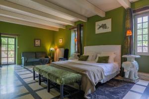 a bedroom with green walls and a bed and a couch at Le Mas D'alzon in Vagnas