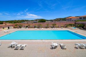 a swimming pool with chaises and lounge chairs next to a resort at Brezza Smeralda- Costa Smeralda in Cala Bitta