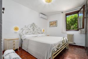 a white bedroom with a bed and a window at Brezza Smeralda- Costa Smeralda in Cala Bitta +16 photos